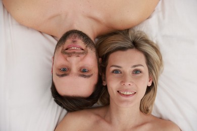 Photo of Spa. Happy couple lying on bed, top view