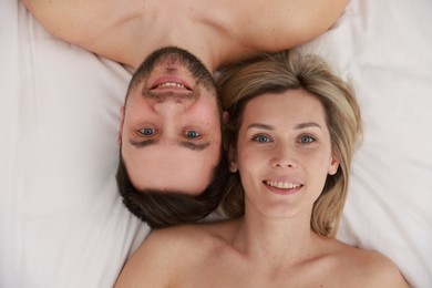 Photo of Spa. Happy couple lying on bed, top view