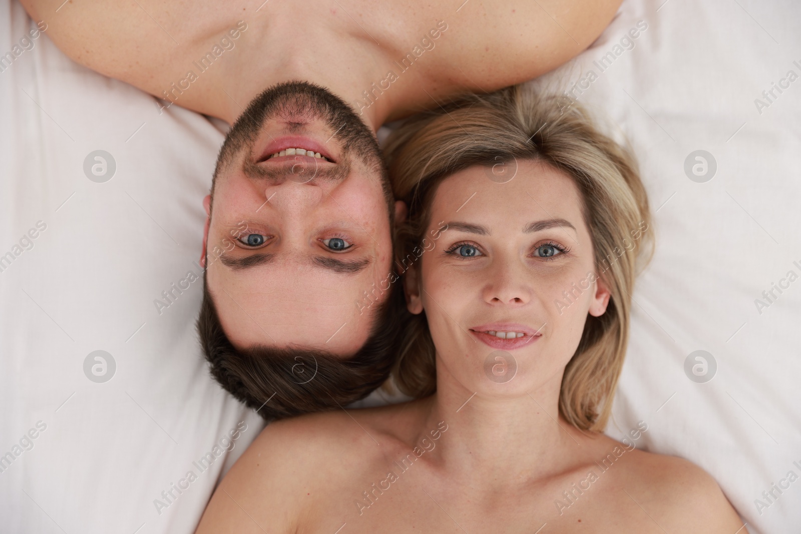 Photo of Spa. Happy couple lying on bed, top view