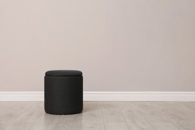 Photo of Stylish pouf near beige wall indoors. Space for text