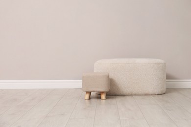 Photo of Stylish poufs near beige wall indoors. Space for text