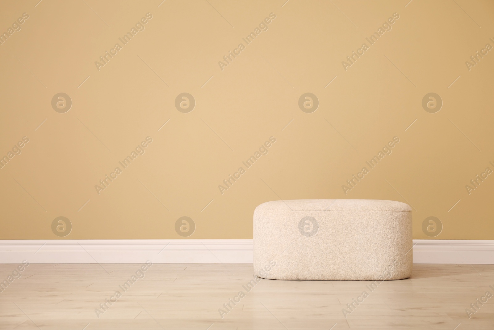 Photo of Stylish comfortable pouf near beige wall indoors, space for text