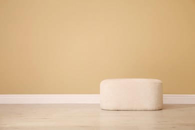 Photo of Stylish comfortable pouf near beige wall indoors, space for text