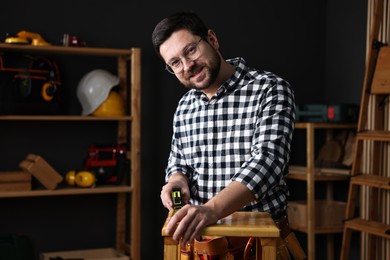 Photo of Professional repairman measuring wooden stool in workshop