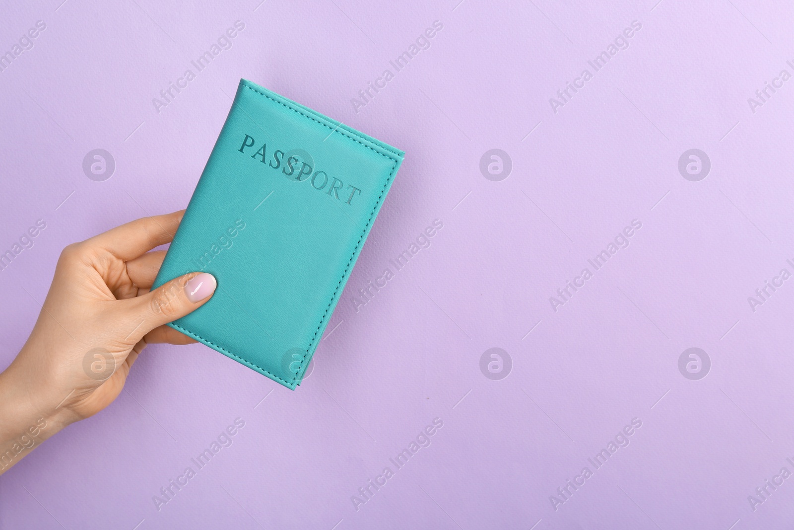 Photo of Woman holding passport in turquoise cover on violet background, closeup. Space for text