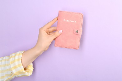 Photo of Woman holding passport in pink cover on violet background, closeup