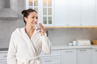 Photo of Beautiful woman drinking water after spa procedure in kitchen, space for text