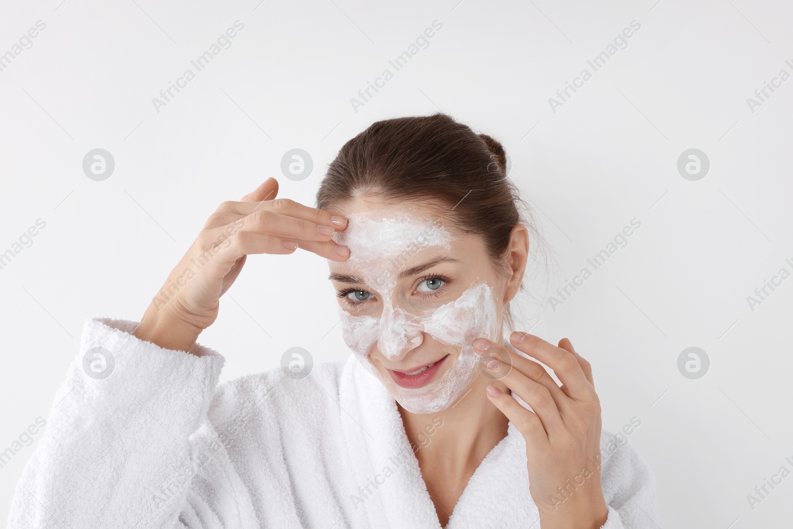 Photo of Spa day. Beautiful woman applying mask onto her face on white background