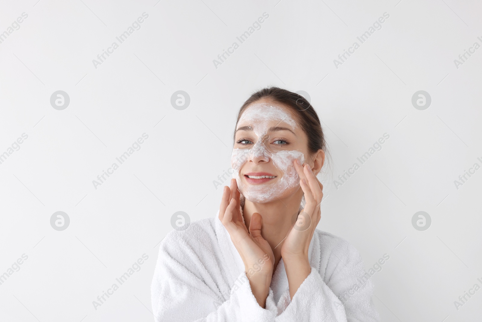 Photo of Spa day. Beautiful woman applying mask onto her face on white background