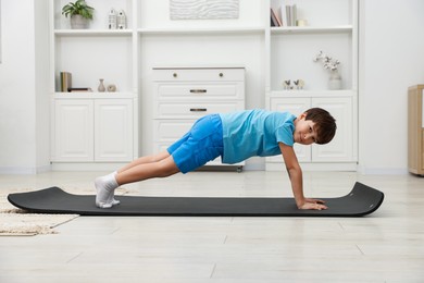 Photo of Boy doing exercise on fitness mat at home. Sport activity