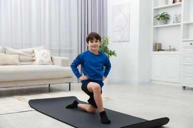 Photo of Boy doing exercise on fitness mat at home. Sport activity