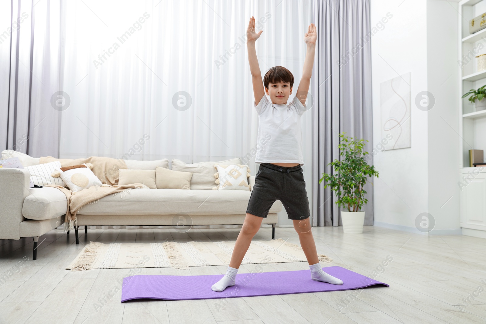 Photo of Boy doing exercise on fitness mat at home. Sport activity