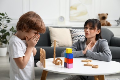 Photo of Psychologist evaluating boy's cognitive functions at table in office, selective focus