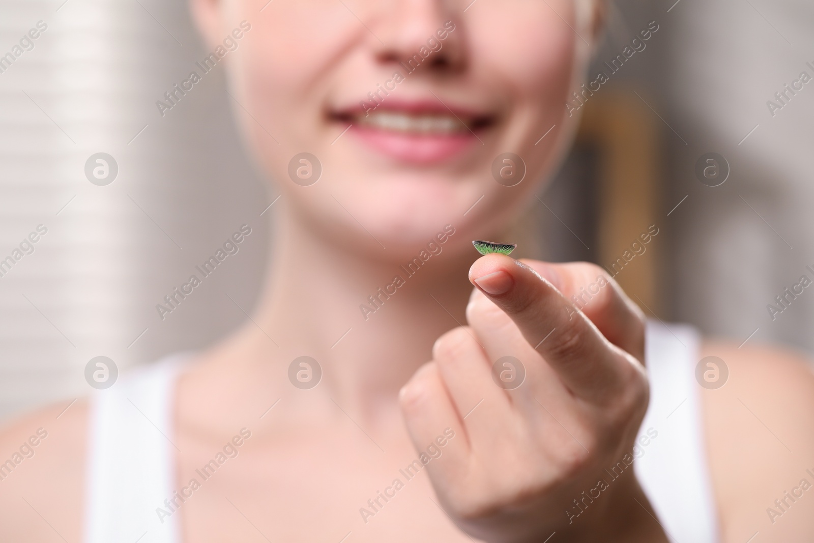 Photo of Young woman with green color contact lens indoors, closeup. Selective focus