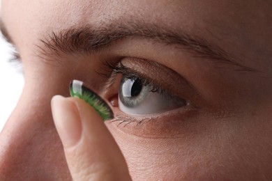 Photo of Woman putting in green color contact lens, closeup