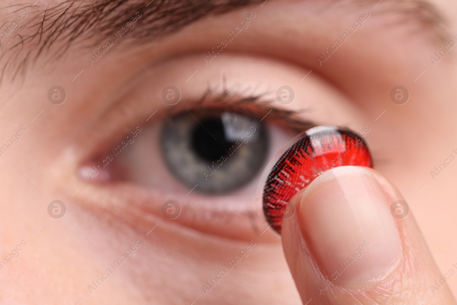 Photo of Woman putting in red color contact lens, closeup