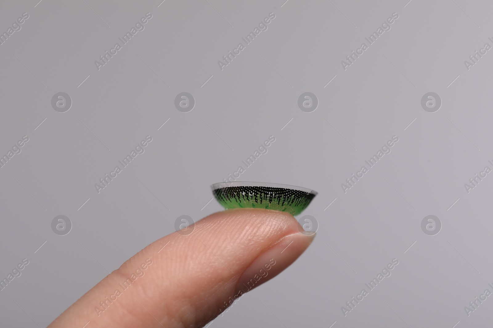 Photo of Woman with green color contact lens on grey background, closeup