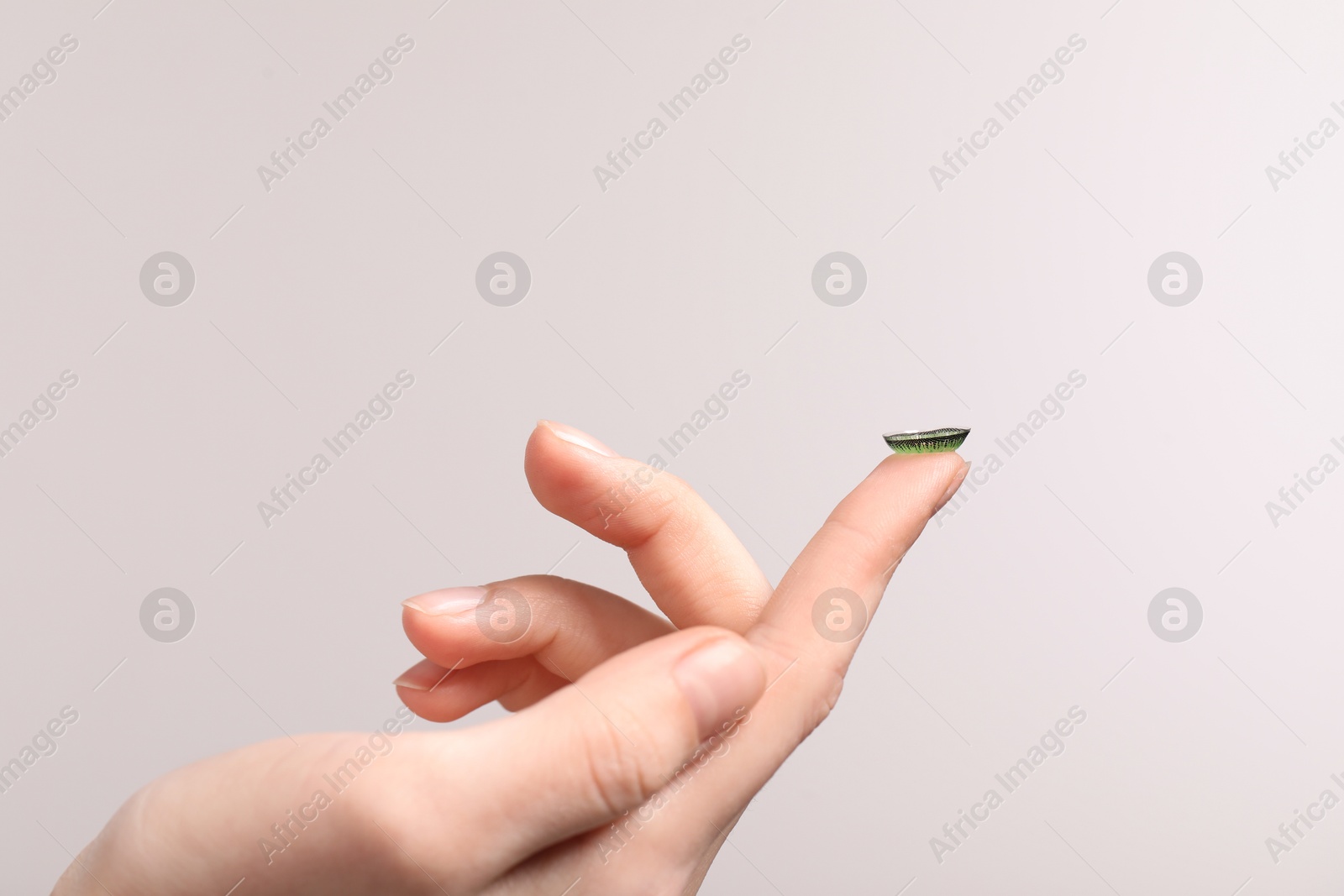 Photo of Woman with green color contact lens on grey background, closeup