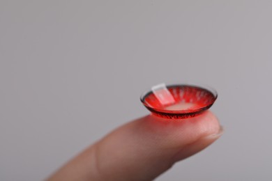 Photo of Woman with red color contact lens on grey background, closeup