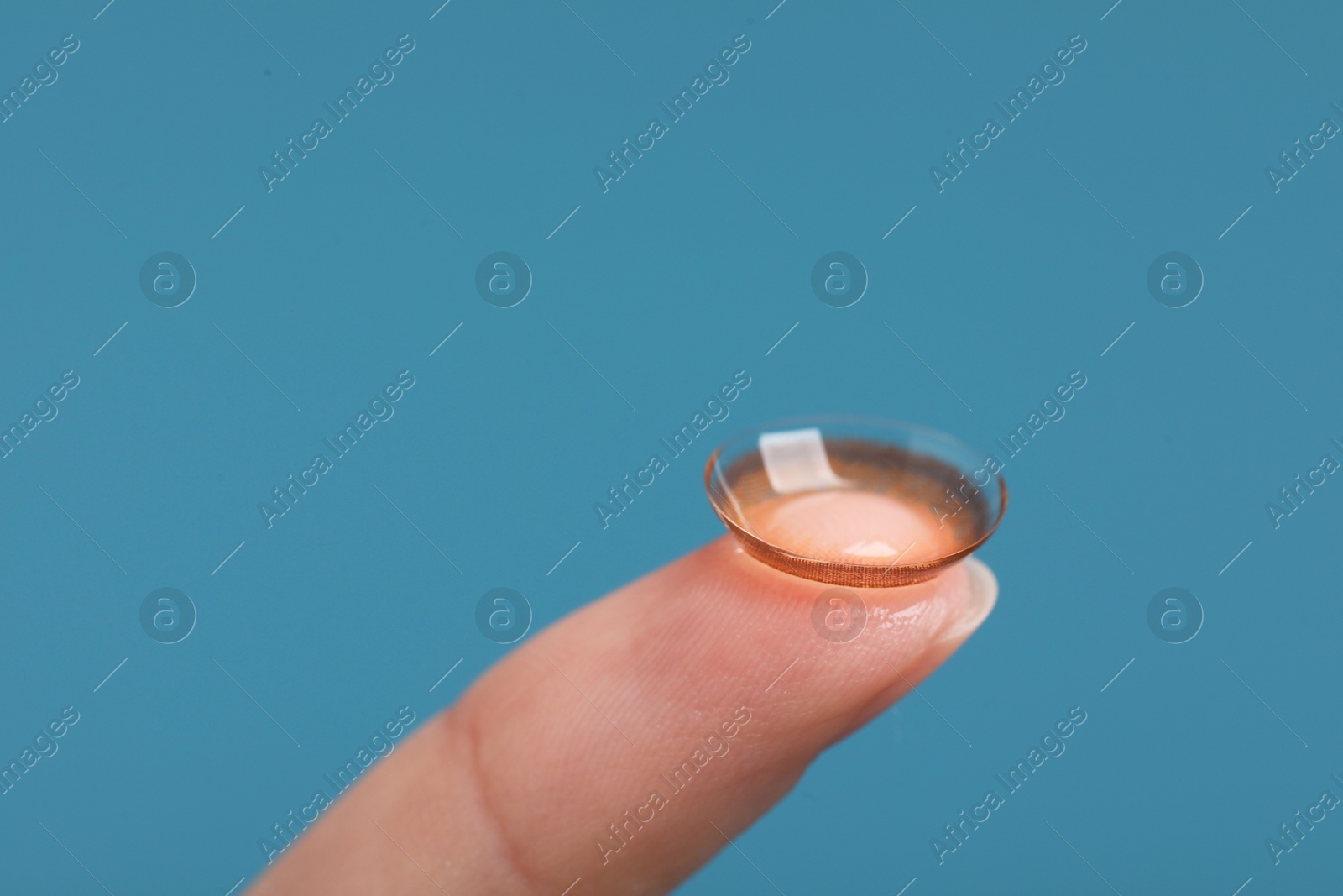 Photo of Woman with color contact lens on light blue background, closeup