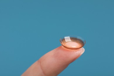 Photo of Woman with color contact lens on light blue background, closeup