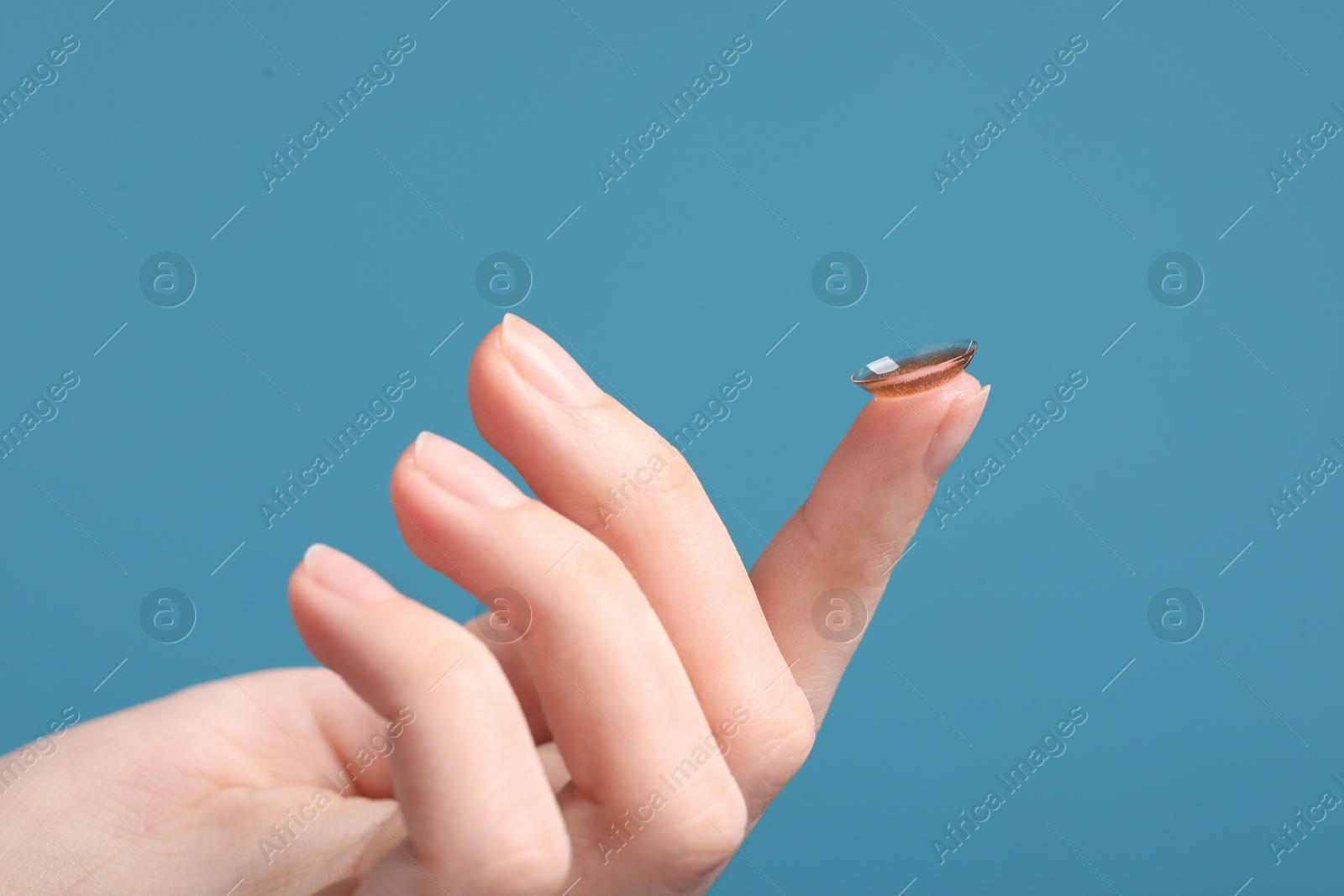 Photo of Woman with color contact lens on light blue background, closeup