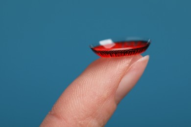 Photo of Woman with red color contact lens on light blue background, closeup