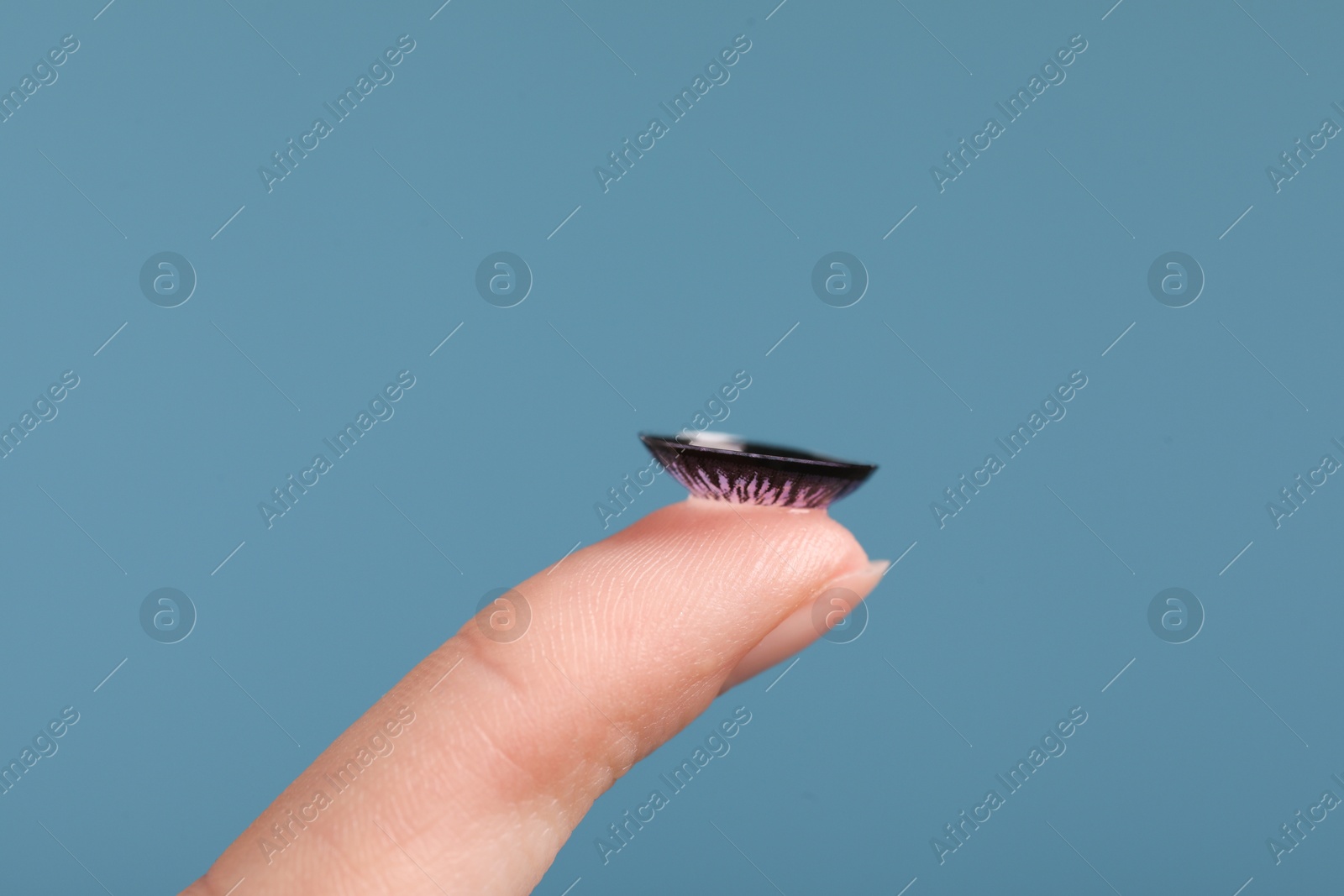 Photo of Woman with color contact lens on light blue background, closeup