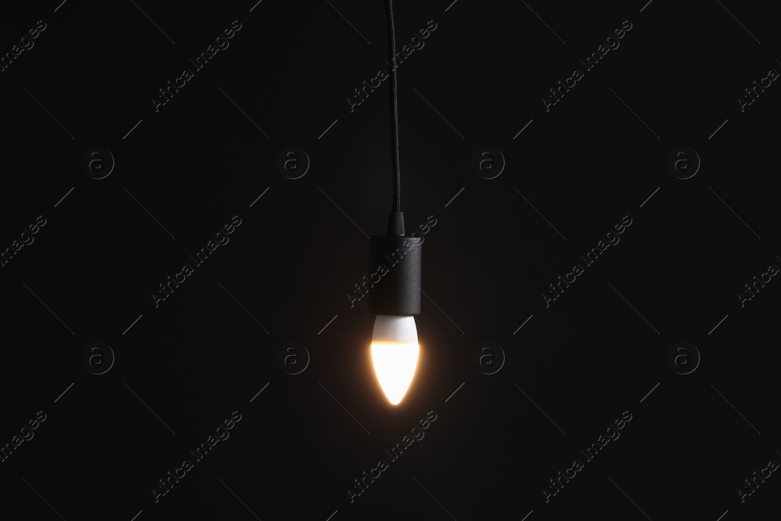 Photo of Glowing light bulb hanging on dark background