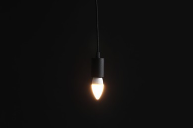 Photo of Glowing light bulb hanging on dark background