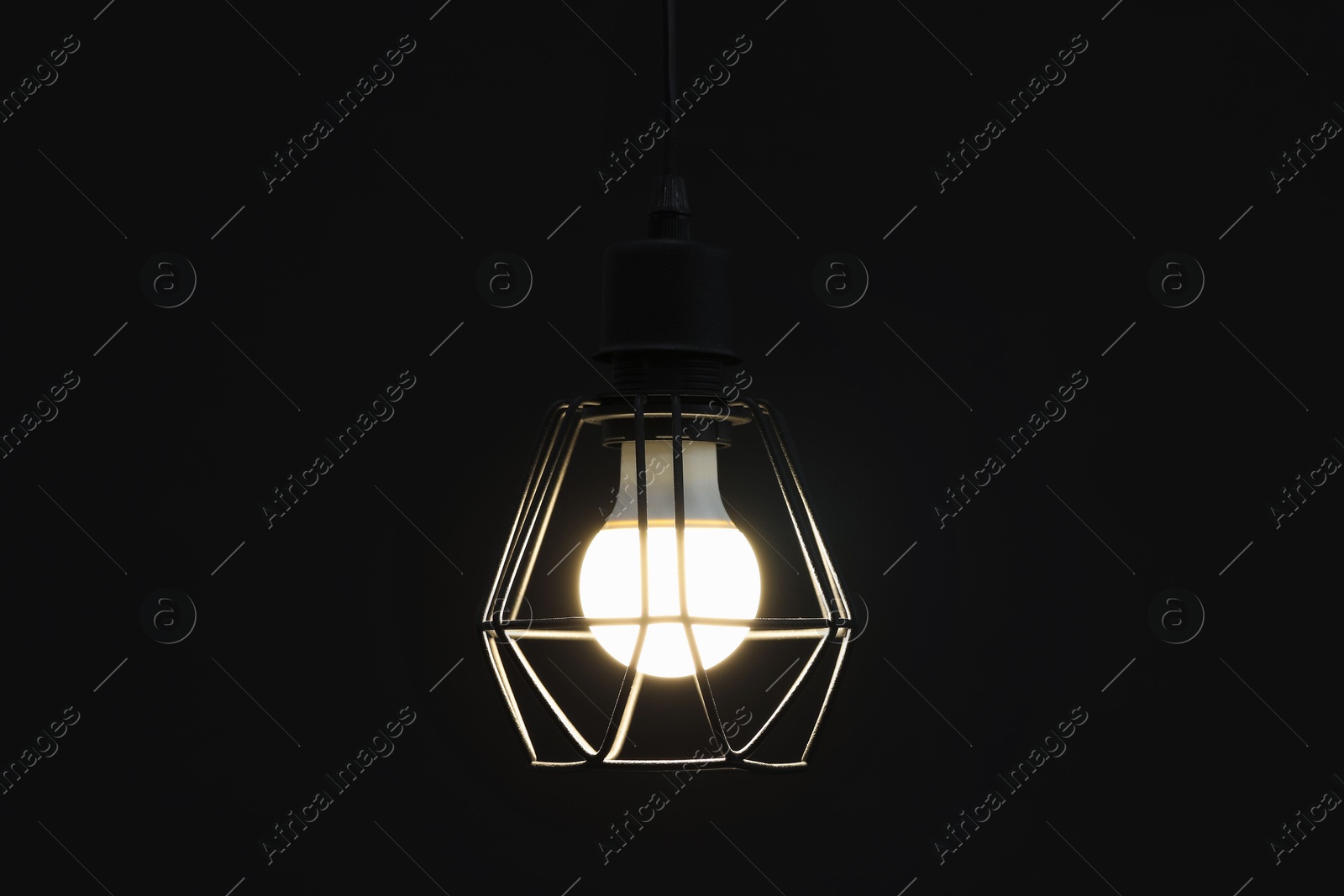 Photo of Chandelier with glowing light bulb hanging on dark background