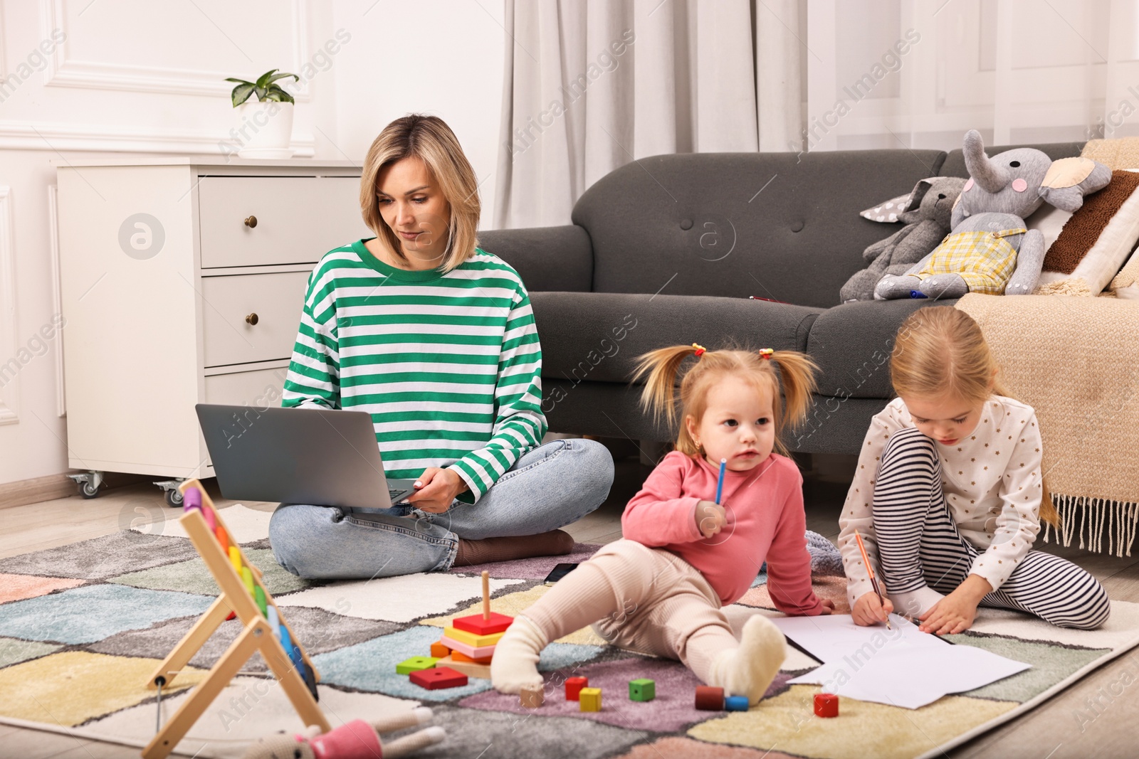 Photo of Single mother working and her children drawing on floor at home