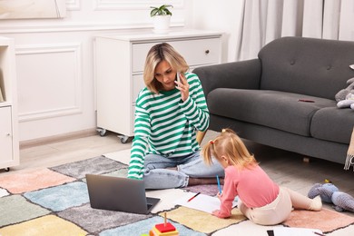 Photo of Work at home. Single mother talking by smartphone and her daughter drawing on floor indoors