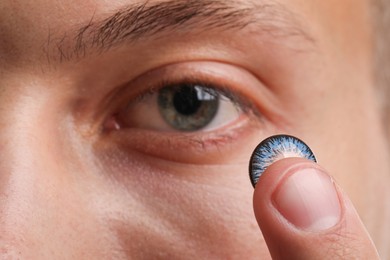 Photo of Man putting color contact lens in his eye, closeup