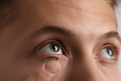 Photo of Man putting color contact lens in his eye, closeup