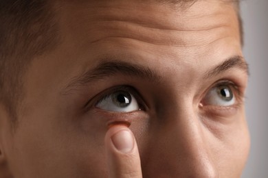 Photo of Man putting color contact lens in his eye, closeup