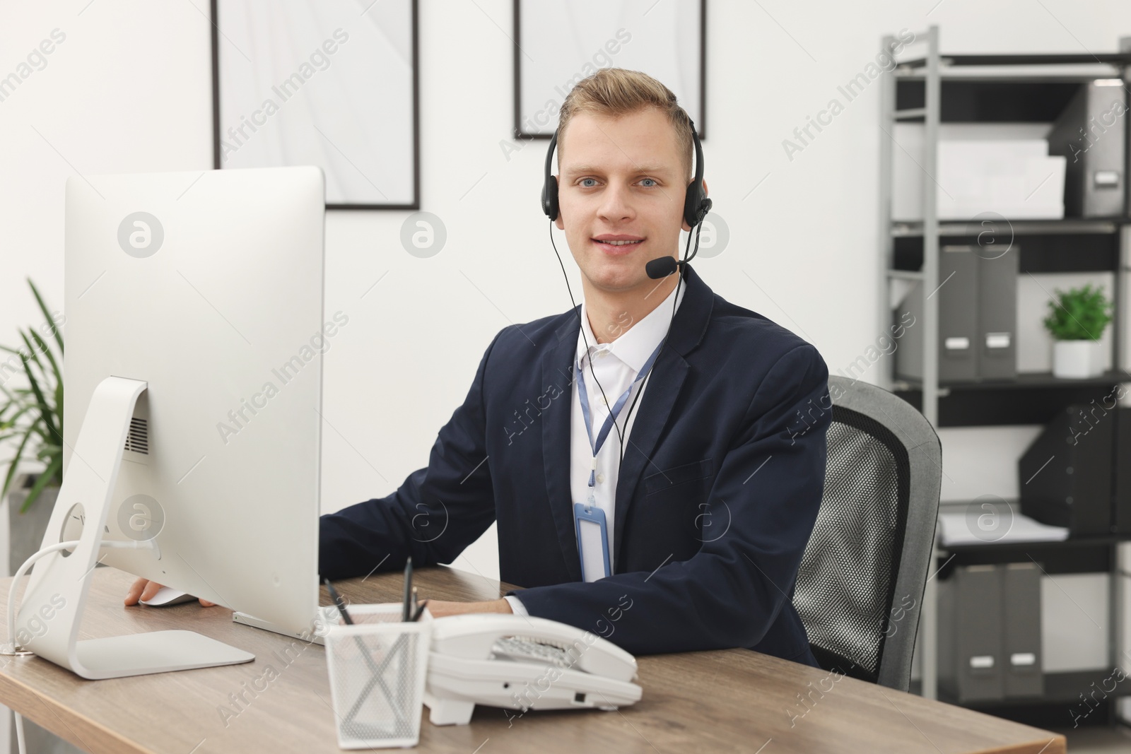 Photo of Technical support call center. Smiling operator working at table in office