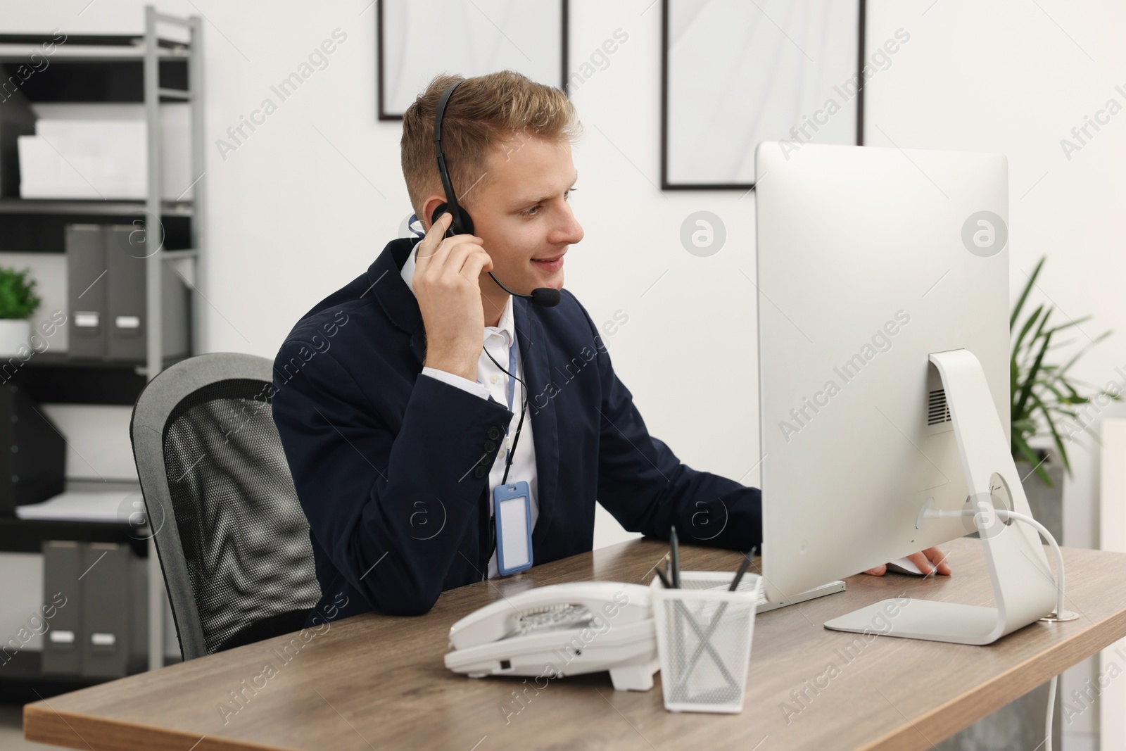 Photo of Technical support call center. Smiling operator working at table in office