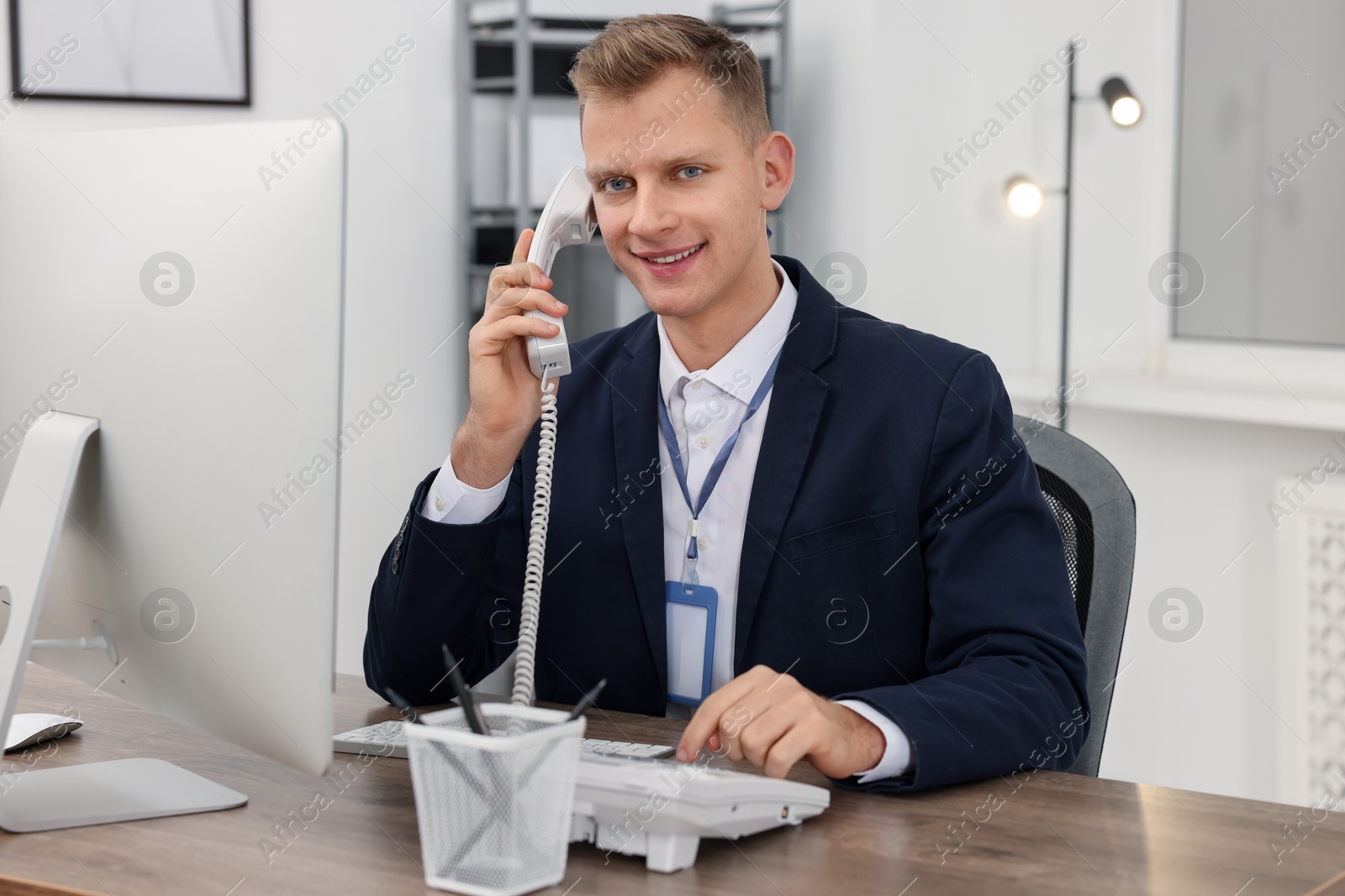 Photo of Technical support call center. Smiling operator working at table in office