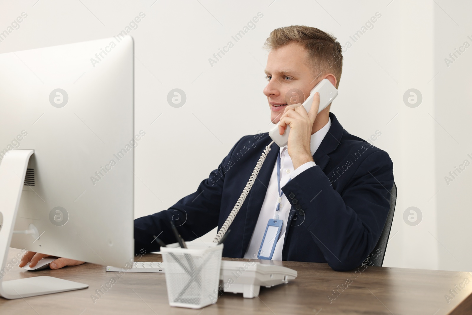 Photo of Technical support call center. Smiling operator working at table in office