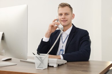 Photo of Technical support call center. Smiling operator working at table in office