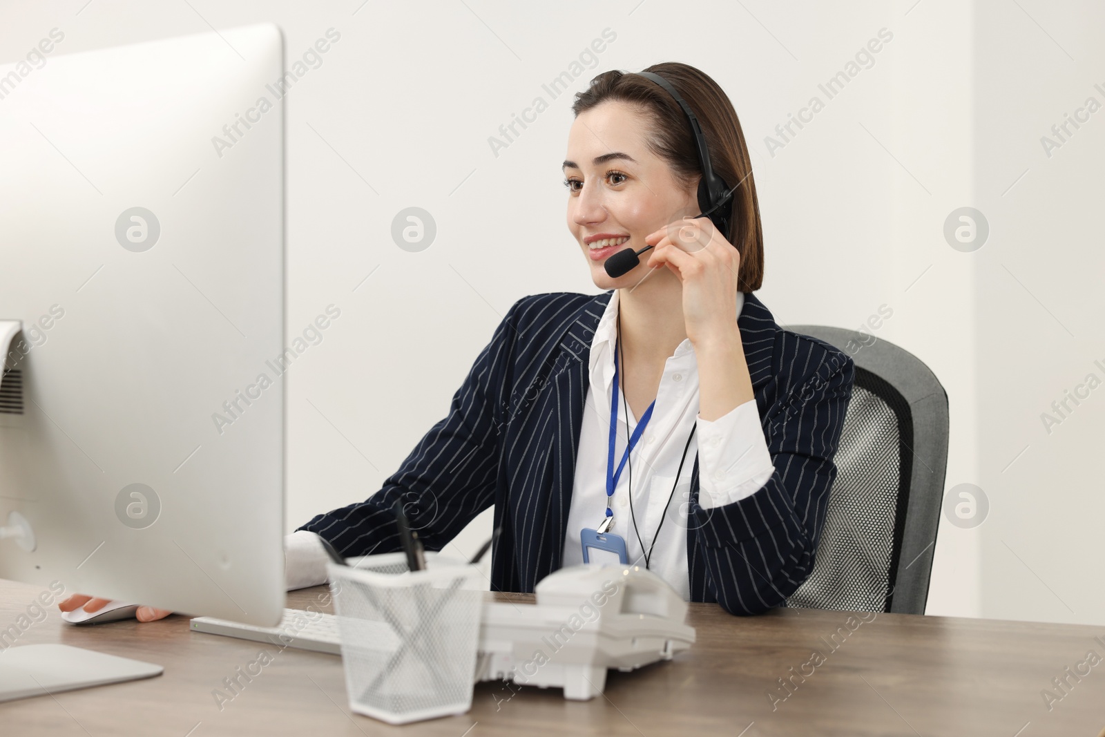 Photo of Technical support call center. Smiling operator working at table in office