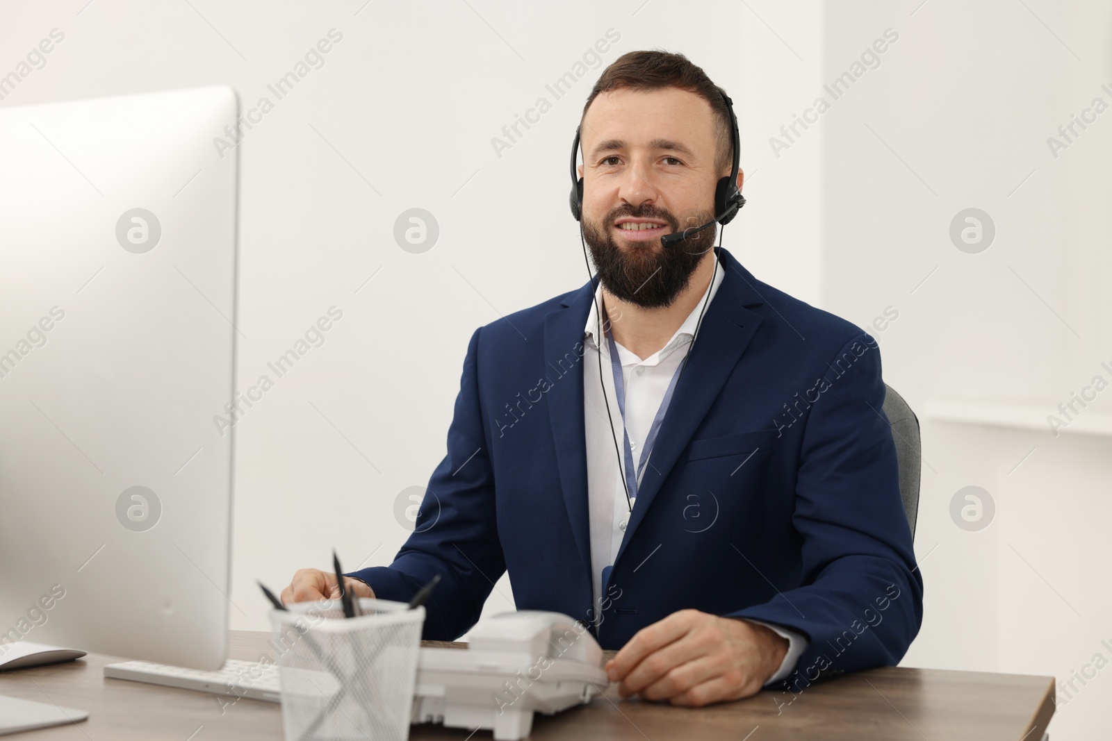 Photo of Technical support call center. Smiling operator working at table in office