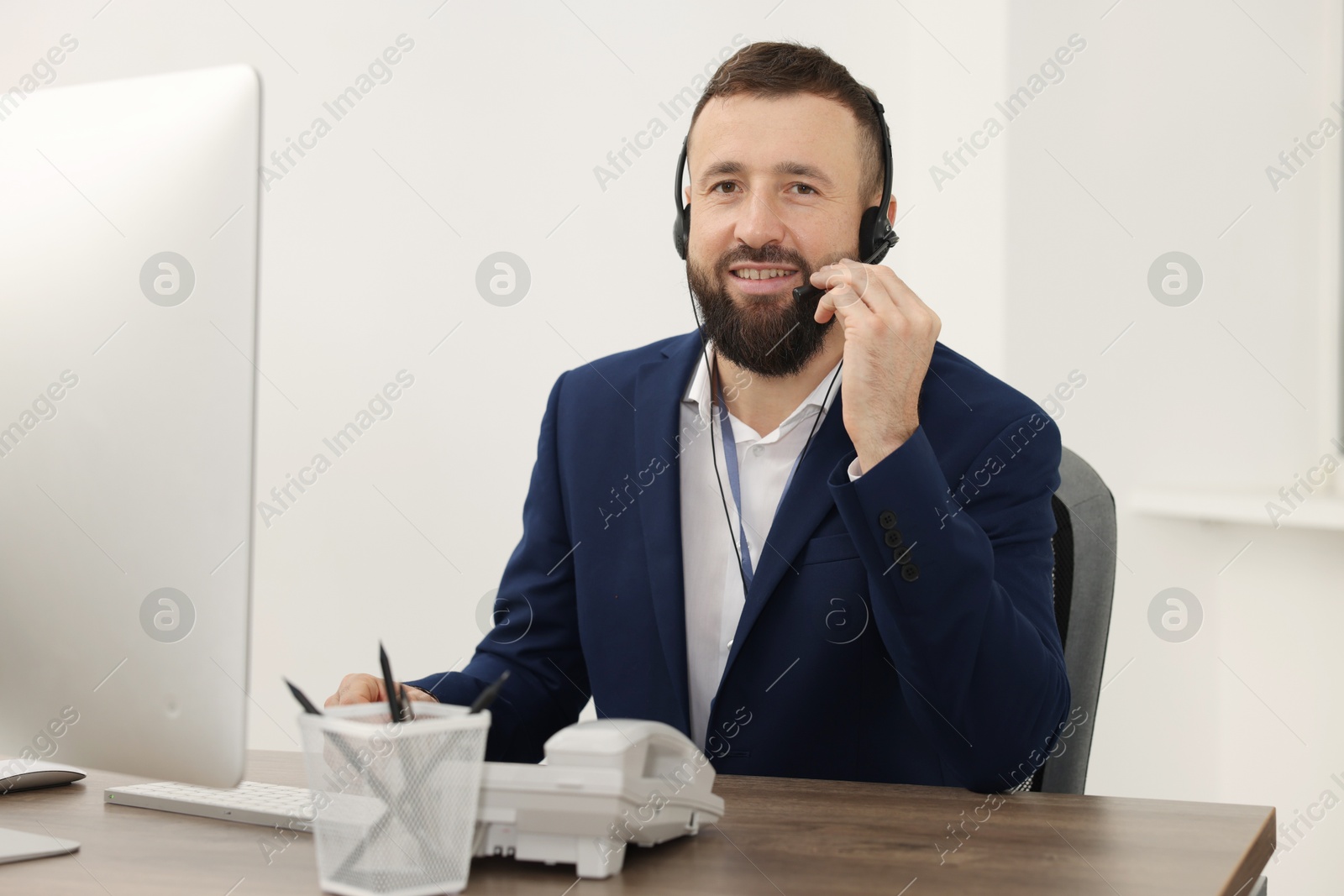 Photo of Technical support call center. Smiling operator working at table in office