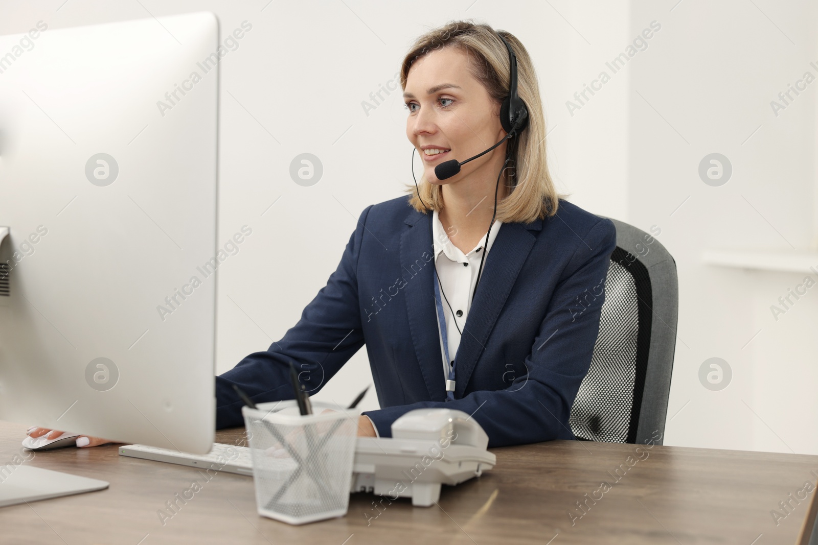 Photo of Technical support call center. Smiling operator working at table in office