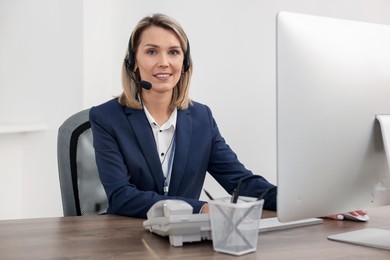 Photo of Technical support call center. Smiling operator working at table in office