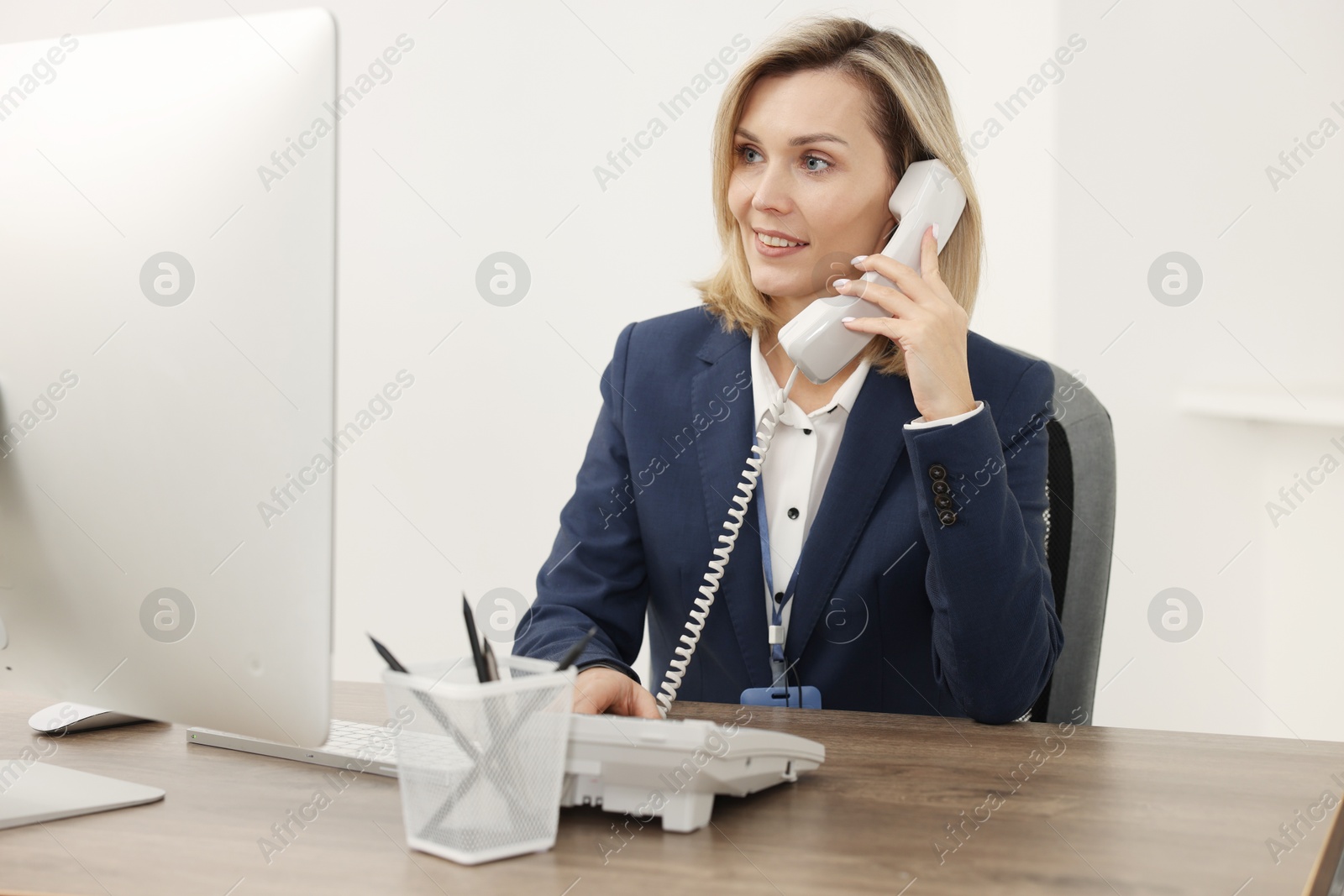 Photo of Technical support call center. Smiling operator working at table in office