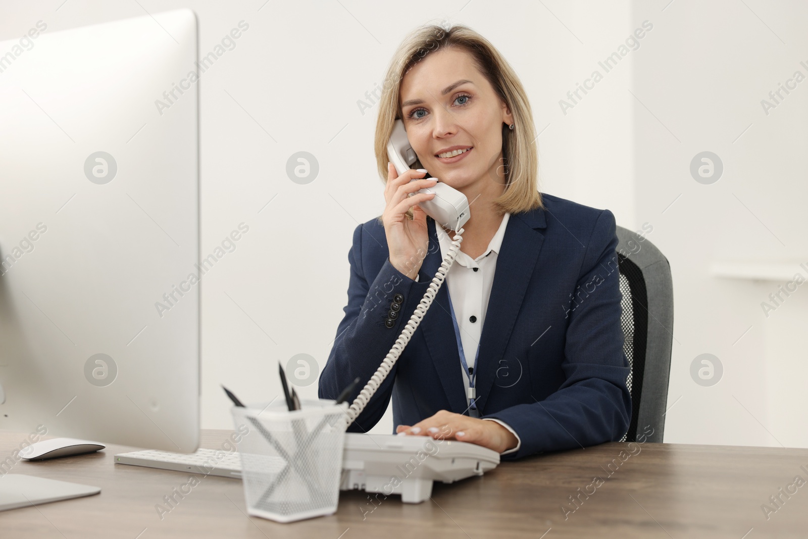 Photo of Technical support call center. Smiling operator working at table in office