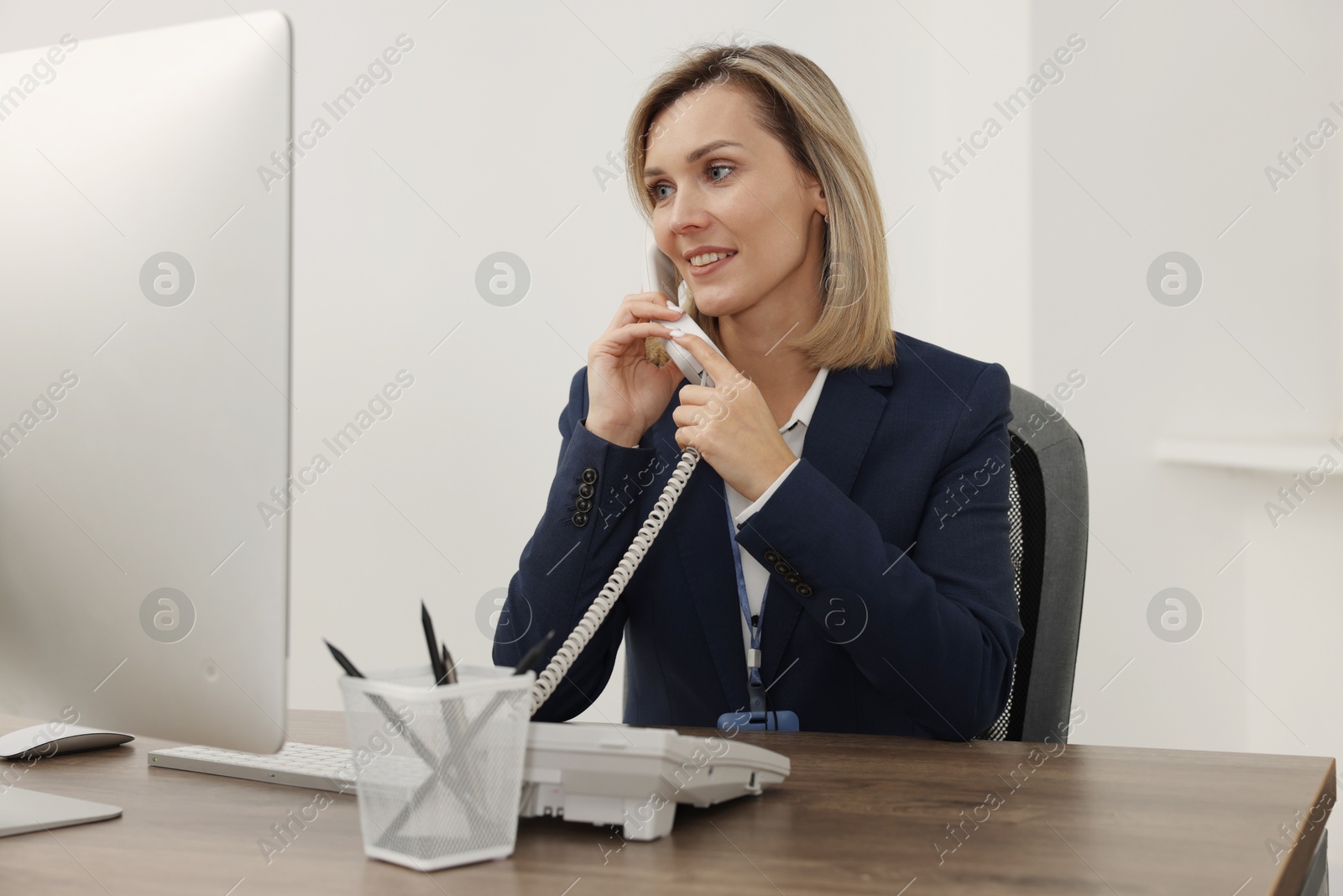 Photo of Technical support call center. Smiling operator working at table in office