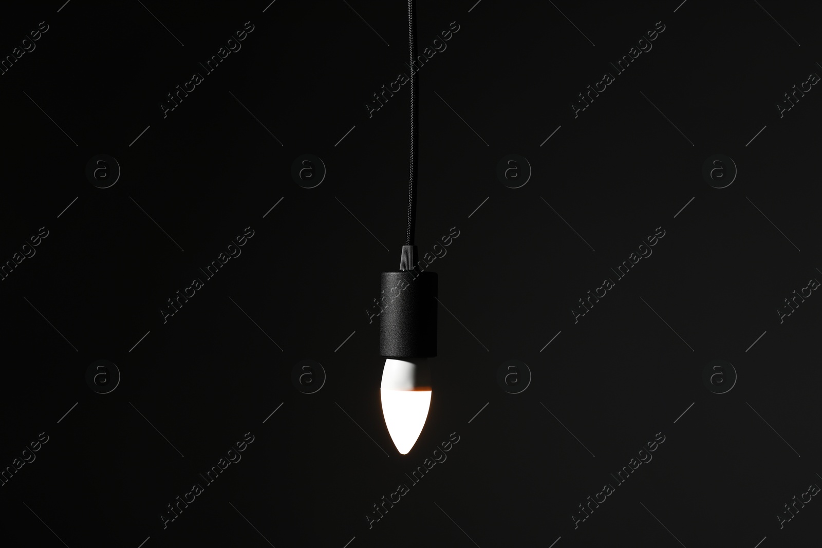 Photo of Glowing light bulb hanging on dark background